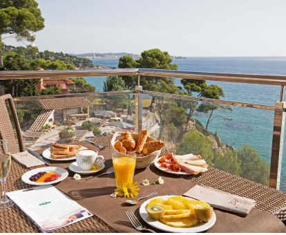 Foto de la terraza con vistas a la playa y una mesa preparada para el desayuno en el Hotel Cap Roig