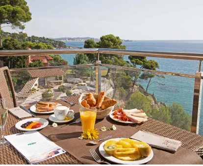 Foto de la terraza con vistas a la playa y una mesa preparada para el desayuno en el Hotel Cap Roig