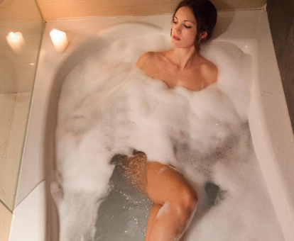 Foto de una chica tomando un baño de espuma en la bañera de hidromasaje de la Suite que se encuentra en el Hotel Granada Palace 