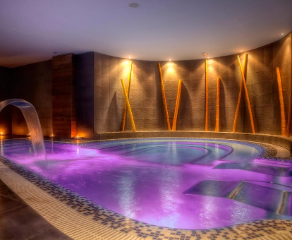 Foto de la piscina cubierta con luz ambiental morada que se encuentra en el Hotel Playa Ribera