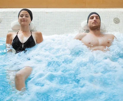Foto de una pareja disfrutando de la piscina de hidromasaje que se encuentra en el RH Bayren Hotel & Spa 4* Sup 
