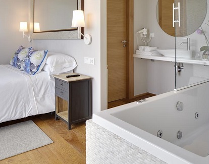 Foto de la bañera de hidromasaje con vistas al campo que además se encuentra junto a la cama en la Suite del Hotel San Prudentzio de Getaria
