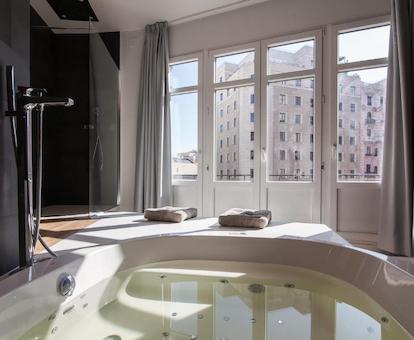 Bañera de hidromasaje circular llenar de agua en la habitación y con vistas a edificios de la GRan Vía de Madrid