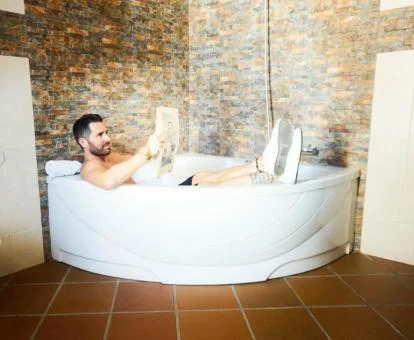 Hombre leyendo en el jacuzzi privado de la Suite.