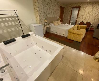 Preciosa suite de un dormitorio con una amplia bañera de hidromasaje privada cerca de la cama. 