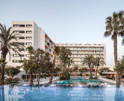 Fabuloso hotel con encanto con amplias piscinas rodeadas de árboles y tumbonas.