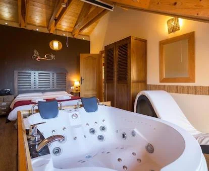 Dormitorio con bañera de hidromasaje privada y sillon tantrico junto a la cama del Apartamento Ático.