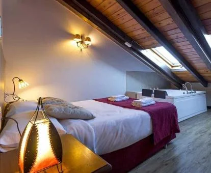 Dormitorio con bañera de hidromasaje privada junto a la cama del Apartamento Ático.