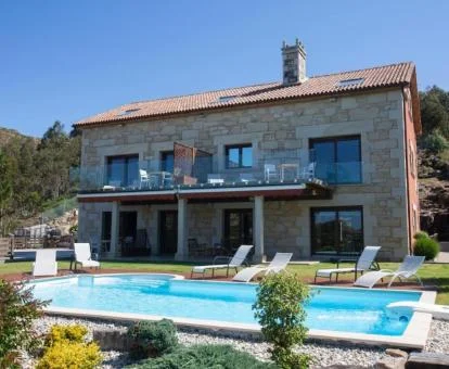 Edificio de piedra de este precioso hotel con piscina exterior y rodeado de vegetación.