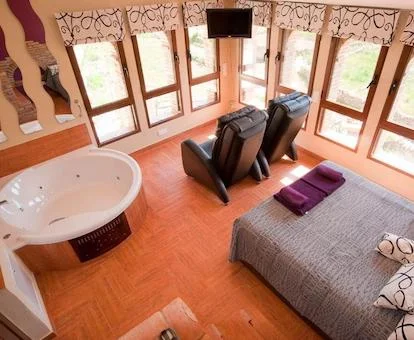 Jacuzzi cerca de la cama y junto a dos sillones para ver el paisaje natural de la casa rural para dos personas Caseta de l'Hort