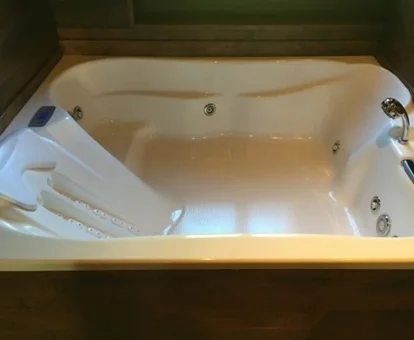 Jacuzzi para dos personas bajo la ventana en el baño de madera con chorros de hidromasaje