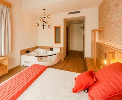 Preciosa suite con bañera de hidromasaje privada junto a la cama de este acogedor hotel.