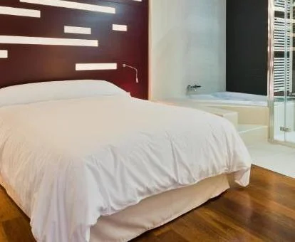 Suite Junior con balcón y jacuzzi privado junto a la cama.