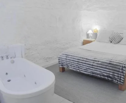 Precioso dormitorio de la suite con cama grande y bañera de hidromasaje privada junto a la cama. 