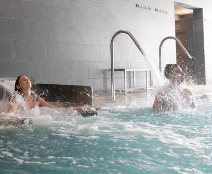 Dos personas disfrutan de la piscina de hidroterapia del centro de bienestar del hotel.