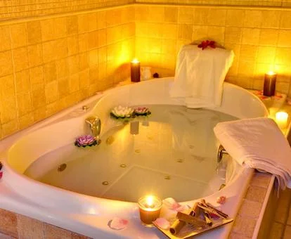 Amplio baño con bañera de hidromasaje de la Suite Junior del hotel lleno de agua y con unas velas en el borde.