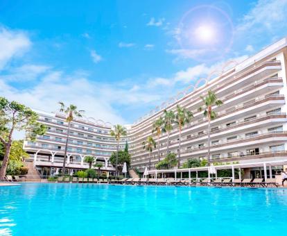 Edificio de este hotel con encanto con una gran piscina exterior rodeada de tumbonas.