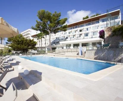 Edificio de este hotel con encanto con amplia piscina y tumbonas.