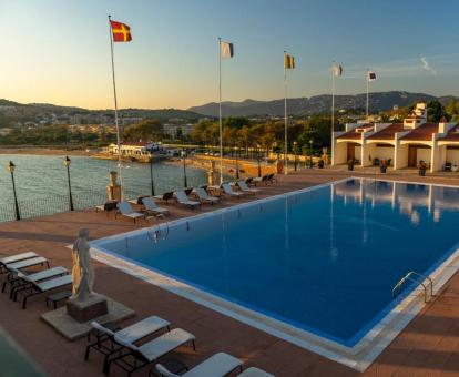 Gran piscina rodeada de tumbonas con vistas al mar de este hotel con encanto.