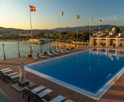 Gran piscina rodeada de tumbonas con vistas al mar de este hotel con encanto.