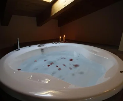 Foto del jacuzzi circular lleno de agua y con luz azul que se encuentra cerca de la cama en la suite del Hotel Spa Adgua de los Mallos