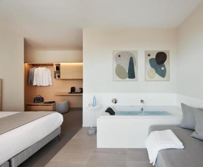 Suite junior con vistas al mar y una amplia bañera de hidromasaje privada junto a la cama.