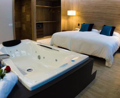 Bañera de hidromasaje privada junto a la cama en la Suite Syrah del hotel.