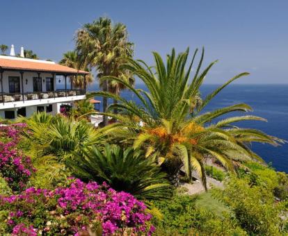 Edificio de este hotel con encanto rodeado de bellos jardines con vistas al mar.
