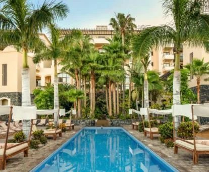 Precioso edificio con bellos jardines, piscina y solarium con camas del hotel.