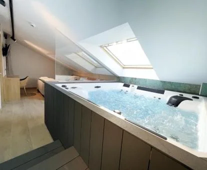 Dormitorio con una espectacular bañera de hidromasaje privada junto a la cama de la Suite Deluxe del hotel.