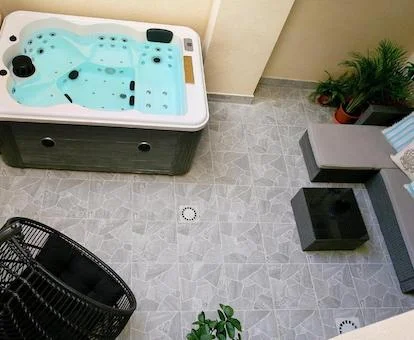 Foto del jacuzzi de gran tamaño para cuatro personas que se encuentra en el patio de la terraza interior del apartamento enfrente de sofá y una silla de descanso