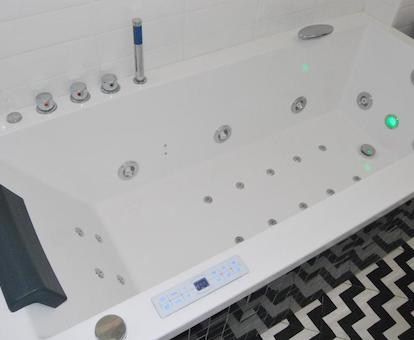 Foto de la bañera de hidromasaje donde se puede ver los controles laterales y la luz verde de cromoterapia preparada para cuando esté lleno el jacuzzi
