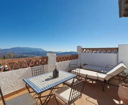 Hermosa terraza con solarium, comedor exterior y vistas a las montañas de uno de los apartamentos del complejo.