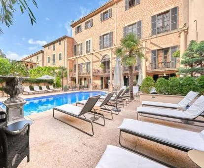 Hermoso edificio con piscina rodeada de tumbonas de este hotel con encanto.