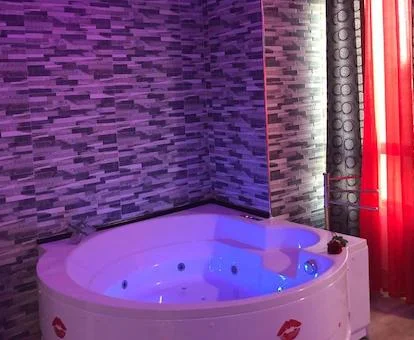 Foto del jacuzzi junto a la ventana bajo unas luces y donde se ven los chorros de hidromasaje, además de unos corazones rojos decorando el exterior