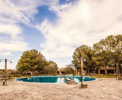 Piscina exterior rodeada de vegetación de este establecimiento rural.