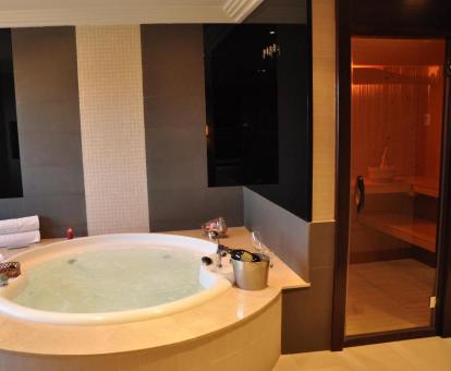 Fabulosa bañera de hidromasaje circular llena de agua y sauna de la suite del hotel.