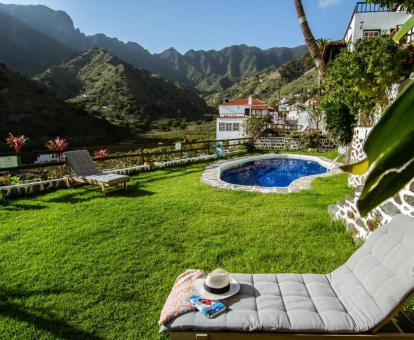 Agradable zona exterior ajardinada con piscina, solarium y espectaculares vistas a las montañas de este complejo de apartamentos.