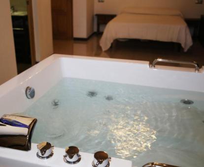 Suite Deluxe con bañera de hidromasaje junto a la cama.