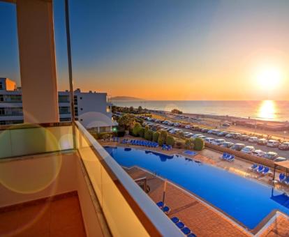 Vista de los exteriores con grandes piscinas de este hotel con encanto junto al mar y un bello atardecer de fondo.