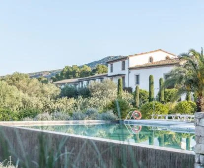 Fabuloso edificio de este hotel con encanto con amplia piscina rodeada de vegetación.