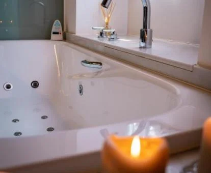 Bañera de hidromasaje privada rodeada de velad de la Suite del hotel.