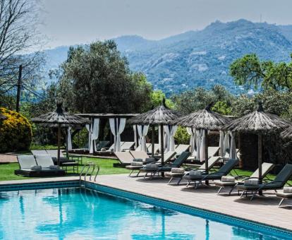 Preciosa piscina rodeada de tumbonas con vistas a las montañas de este hotel con encanto.
