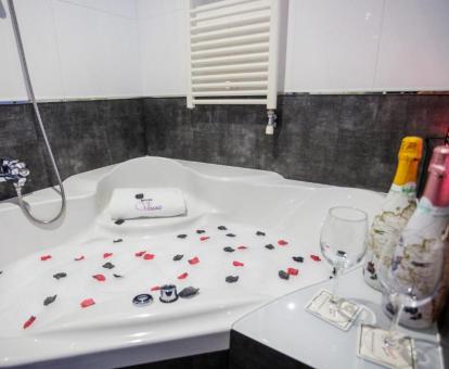 Bañera de hidromasaje privada con decoración romántica y botellas de cava de la suite del hotel.