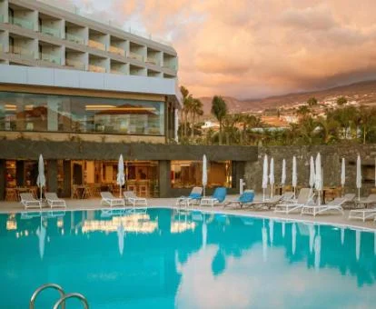 Edificio con piscina exterior rodeada de tumbonas de este hotel con encanto.