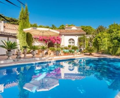 Agradable zona exterior con piscina rodeada de bellos jardines de este hotel con encanto.