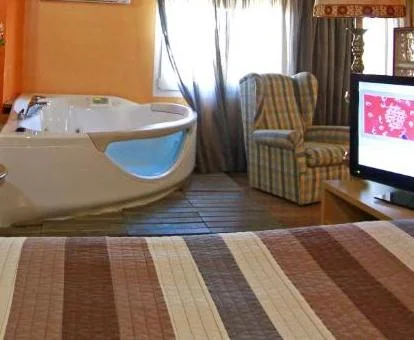 Amplio jacuzzi privado junto a la cama de la Suite Deluxe del hotel.