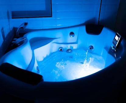 Bañera de hidromasaje en el baño de la habitación Premium Alhambra con los chorros de hidroterapia funcionando y una luz de color azul