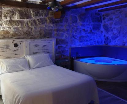 Apartamento de 1 dormitorio con bañera de hidromasaje iluminada y con los chorros de hidromasaje encendidos que se encuentra junto a la cama.