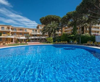 Hotel con encanto con amplia piscina al aire libre con jardines y tumbonas.